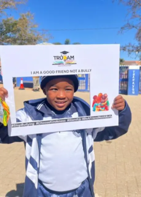 A learner holding an “I am a good friend, not a bully” photo frame