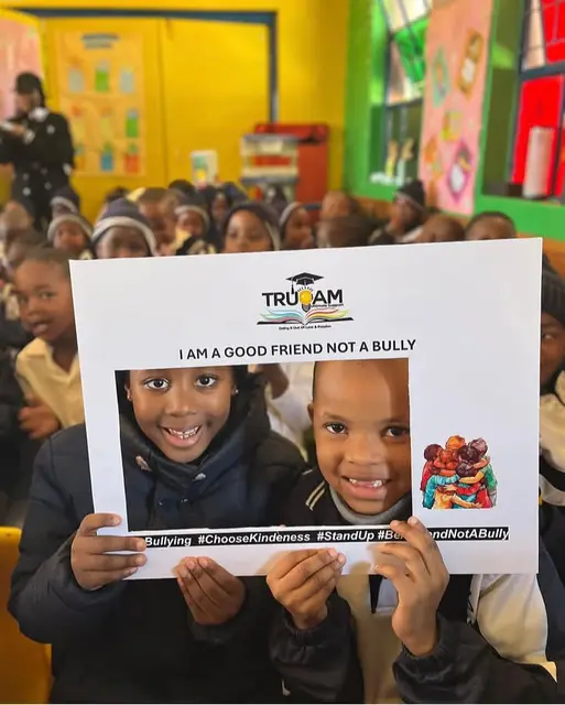 Two learners posing with the “I am a good friend, not a bully” frame