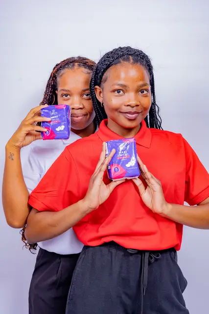Two Her Essence volunteers showing sanitary pads for donation