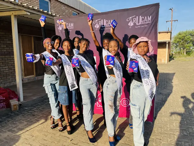 Miss Sekgosese contestants raising sanitary towel packs in front of the TruCam banner
