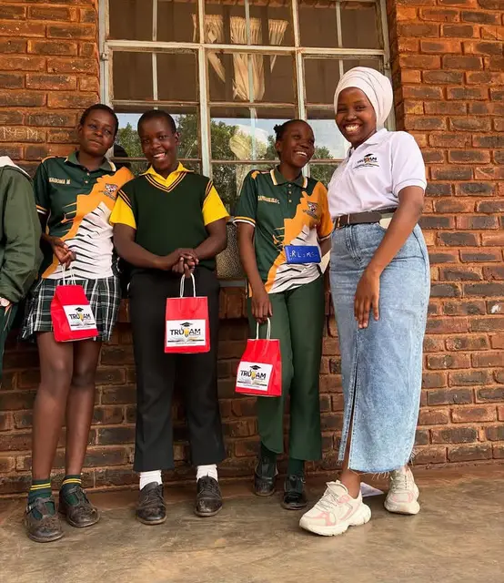 Learners holding TruCam gift bags alongside a TruCam team member